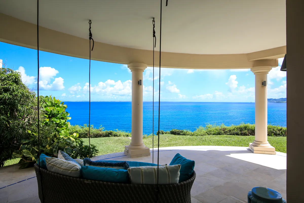 Villa Mes Amis: Covered patio with a suspended daybed swing overlooking the lawn and ocean