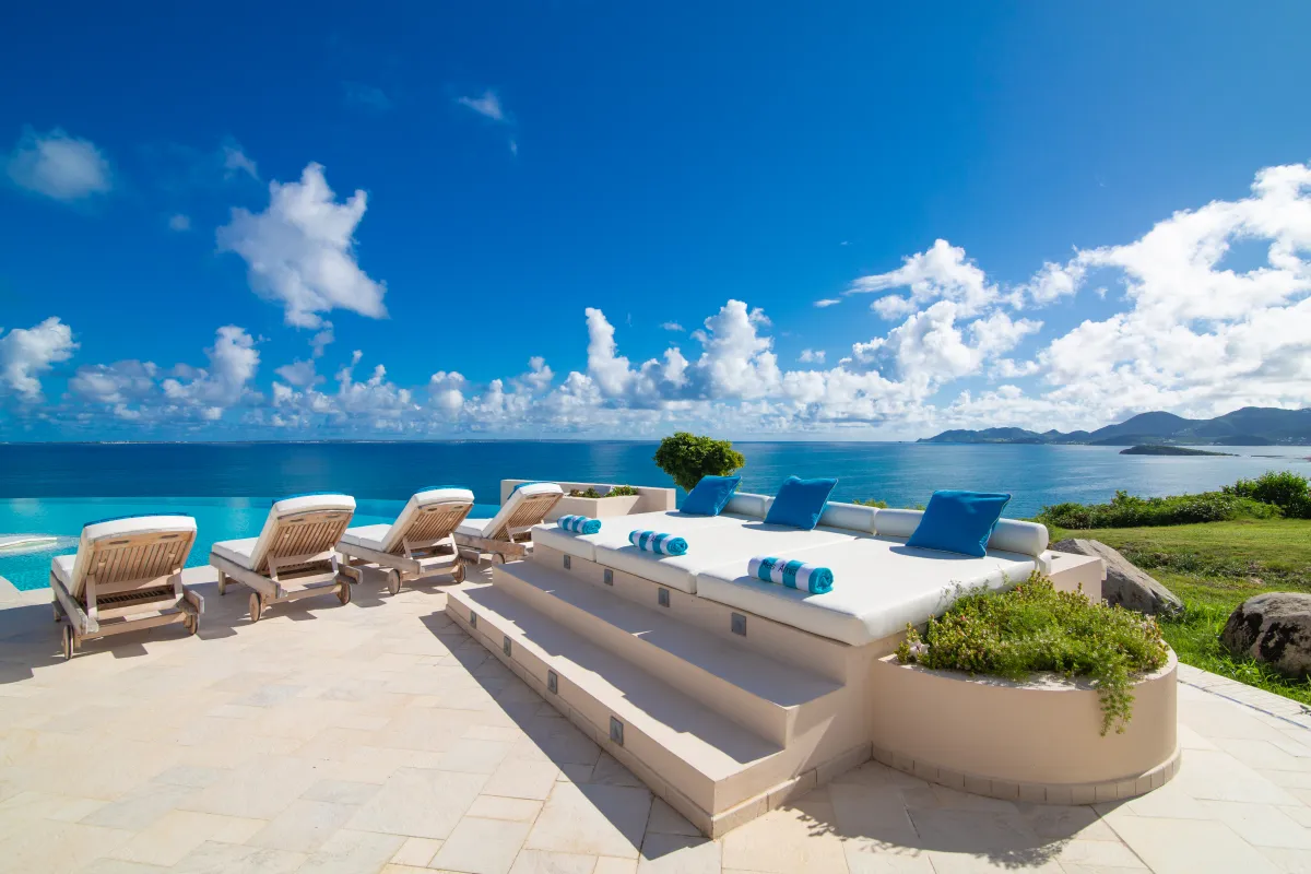 Villa Mes Amis: Sun loungers and a raised daybed on a tiled terrace overlooking the ocean
