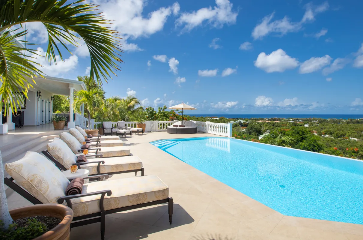 Villa Mille Fleurs: Infinity swimming pool with cushioned sun loungers overlooking lush greenery and the sea