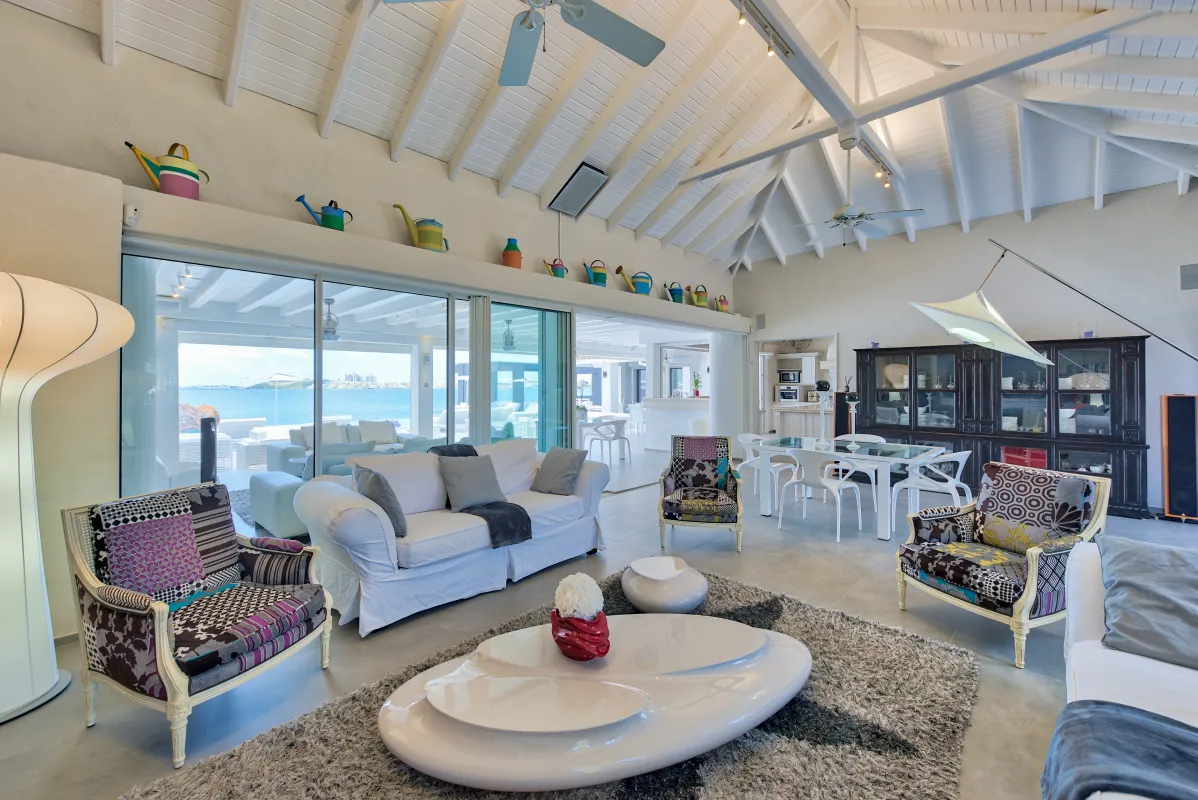 Villa Mirabelle: Open-plan living room with vaulted ceiling and sliding glass doors framing ocean views