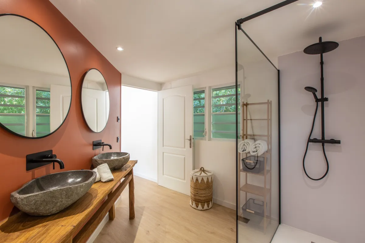 Villa Monchal: Modern bathroom with double stone sinks, terracotta accent wall, and a walk-in shower