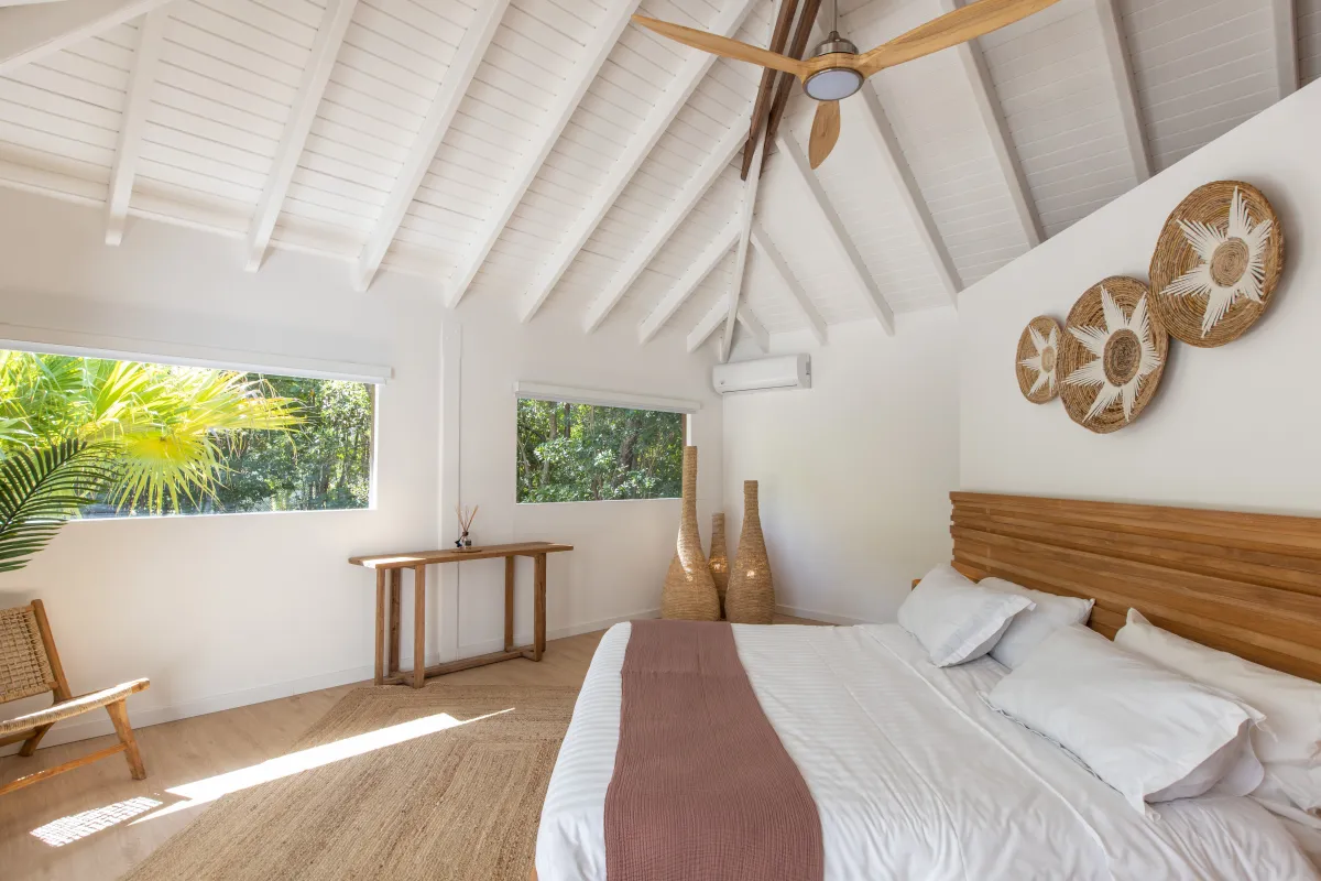 Villa Monchal: Bedroom with a king bed, wooden headboard, vaulted ceiling, and lush garden views
