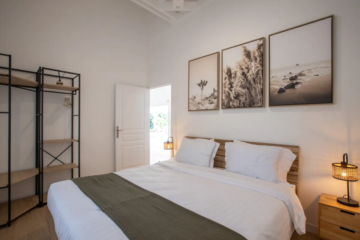 Villa Monchal: Bedroom with a wooden headboard bed, framed wall prints, and open doorway