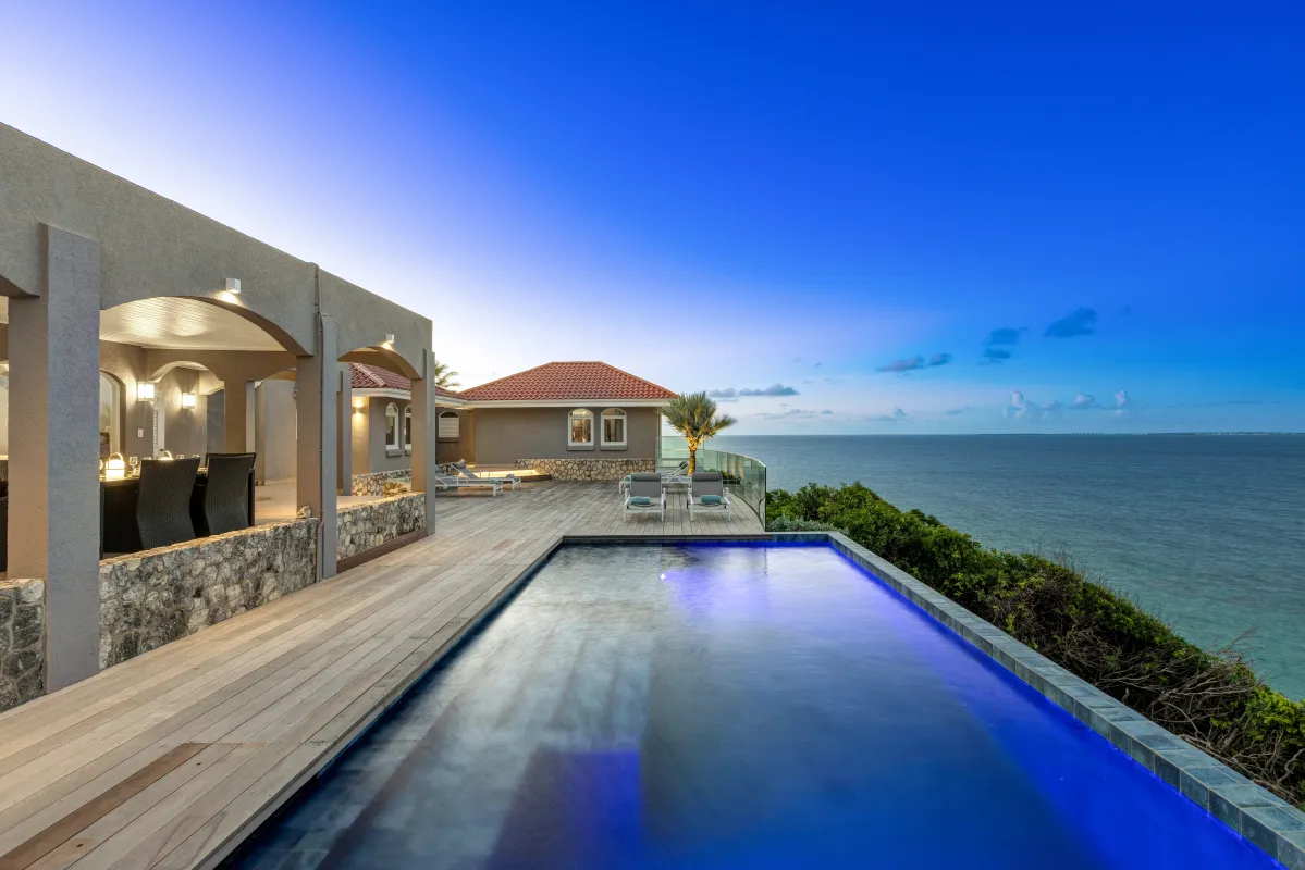 Villa Mongoose Run: Infinity pool and wooden deck overlooking the ocean at dusk