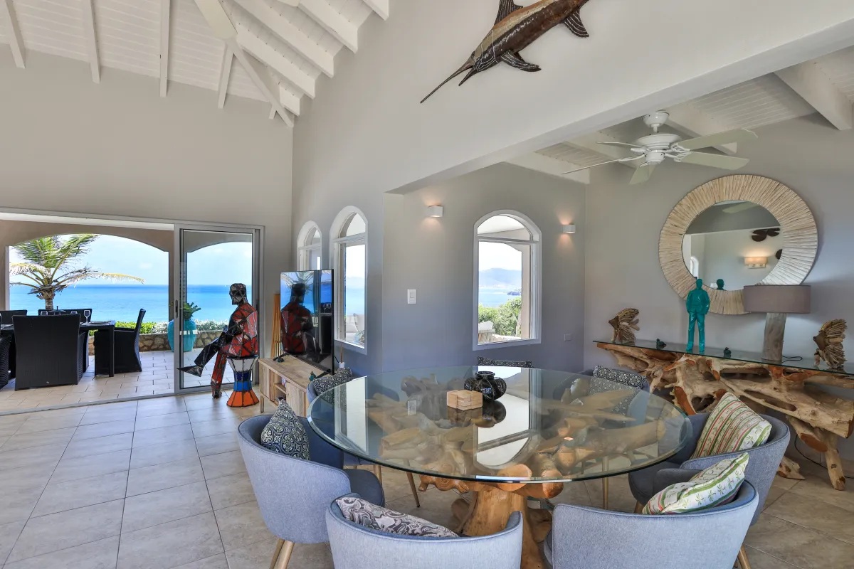 Villa Mongoose Run: Dining area with glass-top table, vaulted ceiling, and sliding doors opening to the terrace