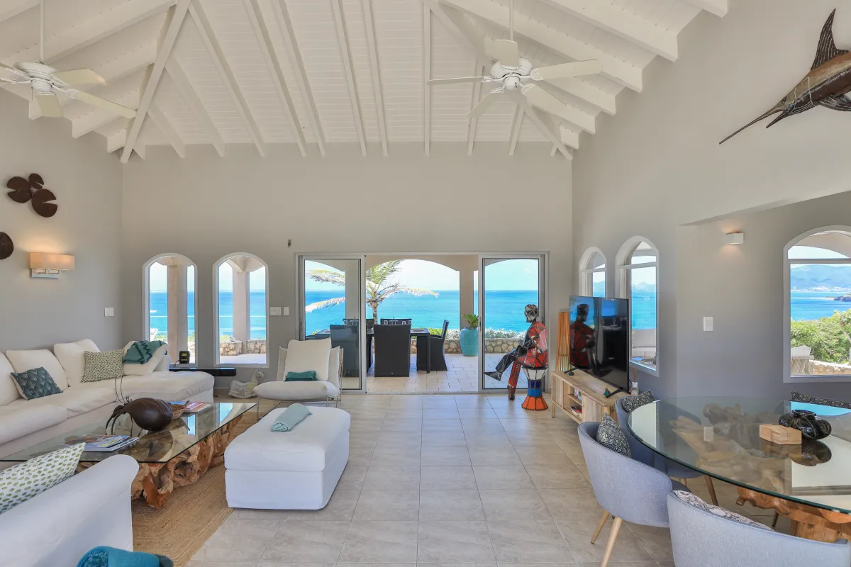 Villa Mongoose Run: Living area with vaulted ceiling, seating, and glass doors opening to an ocean view