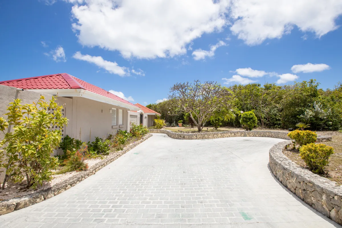 Villa Mongoose Run: Paved driveway leading toward a villa surrounded by tropical landscaping and stone walls
