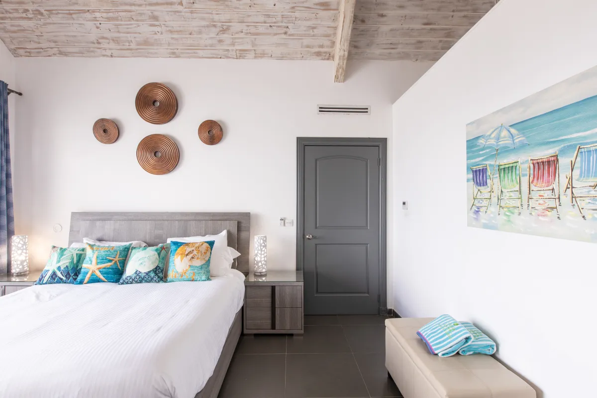 Villa Monte Verde: Bedroom with a bed, beach-themed pillows, nightstands, and whitewashed wood ceiling