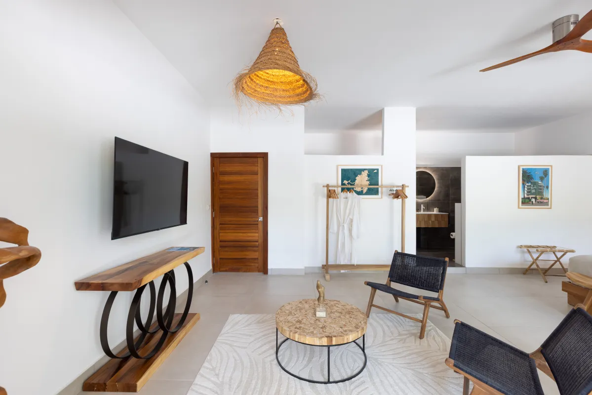 Villa Nirvana: Bedroom seating area with wall-mounted television, woven armchairs, and ensuite bathroom entrance