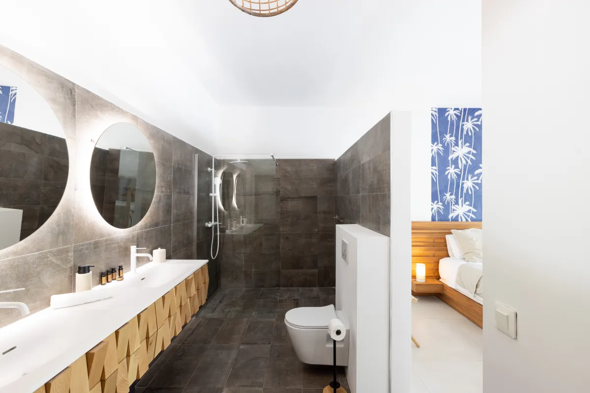 Villa Nirvana: Modern ensuite bathroom with double vanity, illuminated round mirrors, and walk-in shower