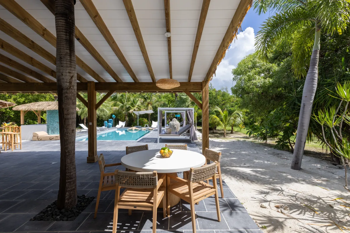Villa Nirvana: Covered patio with a dining table and chairs overlooking a swimming pool and tropical palms