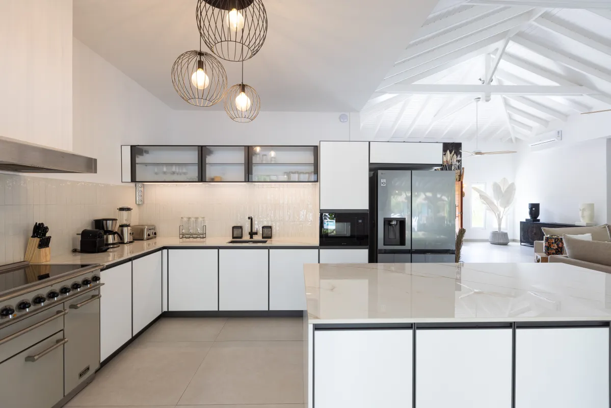 Villa Nirvana: Modern open plan kitchen with white cabinetry, marble countertops, and contemporary pendant lighting