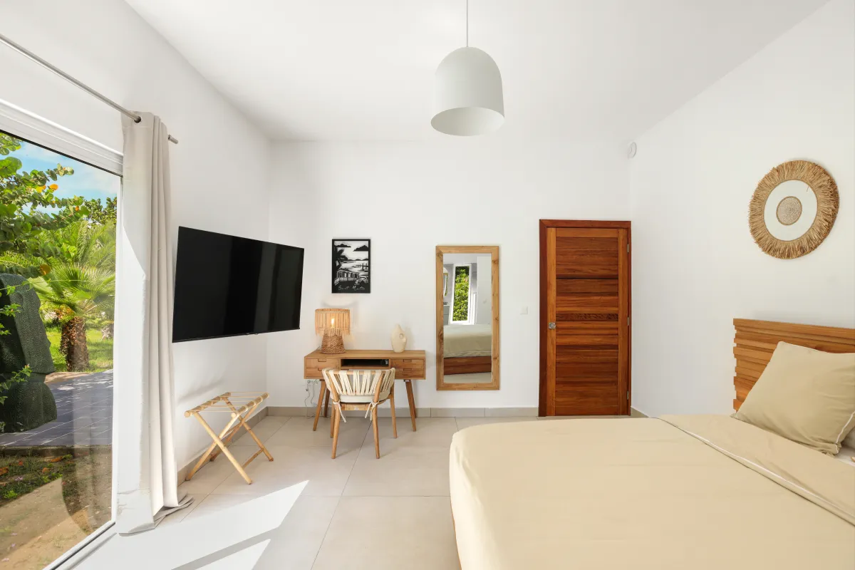 Villa Nirvana: Bedroom with wooden desk, wall-mounted television, and glass door leading to garden