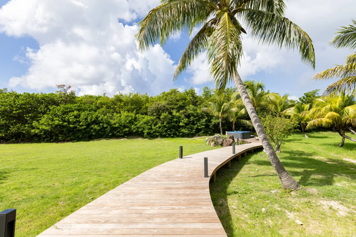 Villa Nirvana: Curving wooden boardwalk across a lawn leading to palm trees and a hot tub