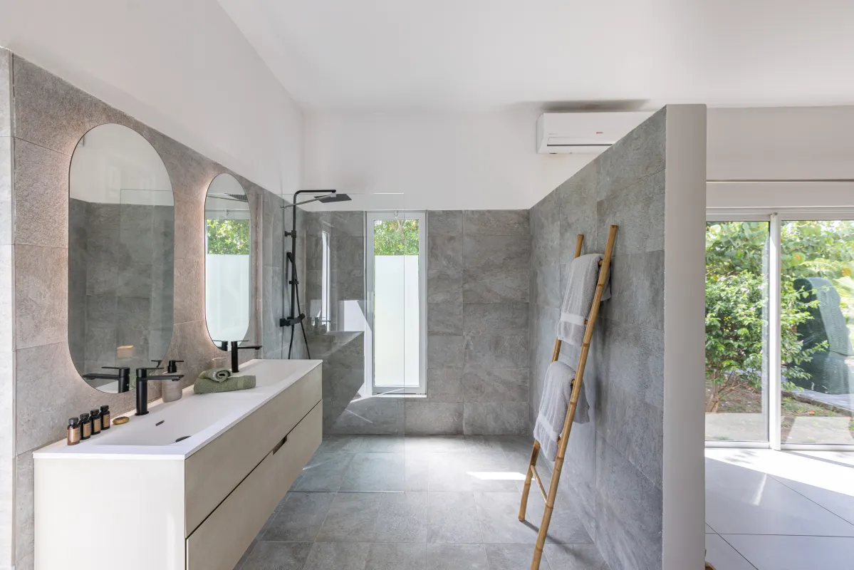 Villa Nirvana: Modern bathroom with double vanity, backlit mirrors, and walk-in shower with grey stone tiles