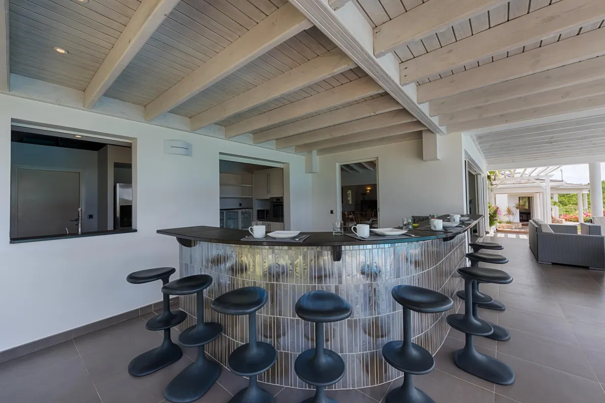 Villa No Limit: Curved outdoor bar counter with modern bar stools under a covered terrace ceiling