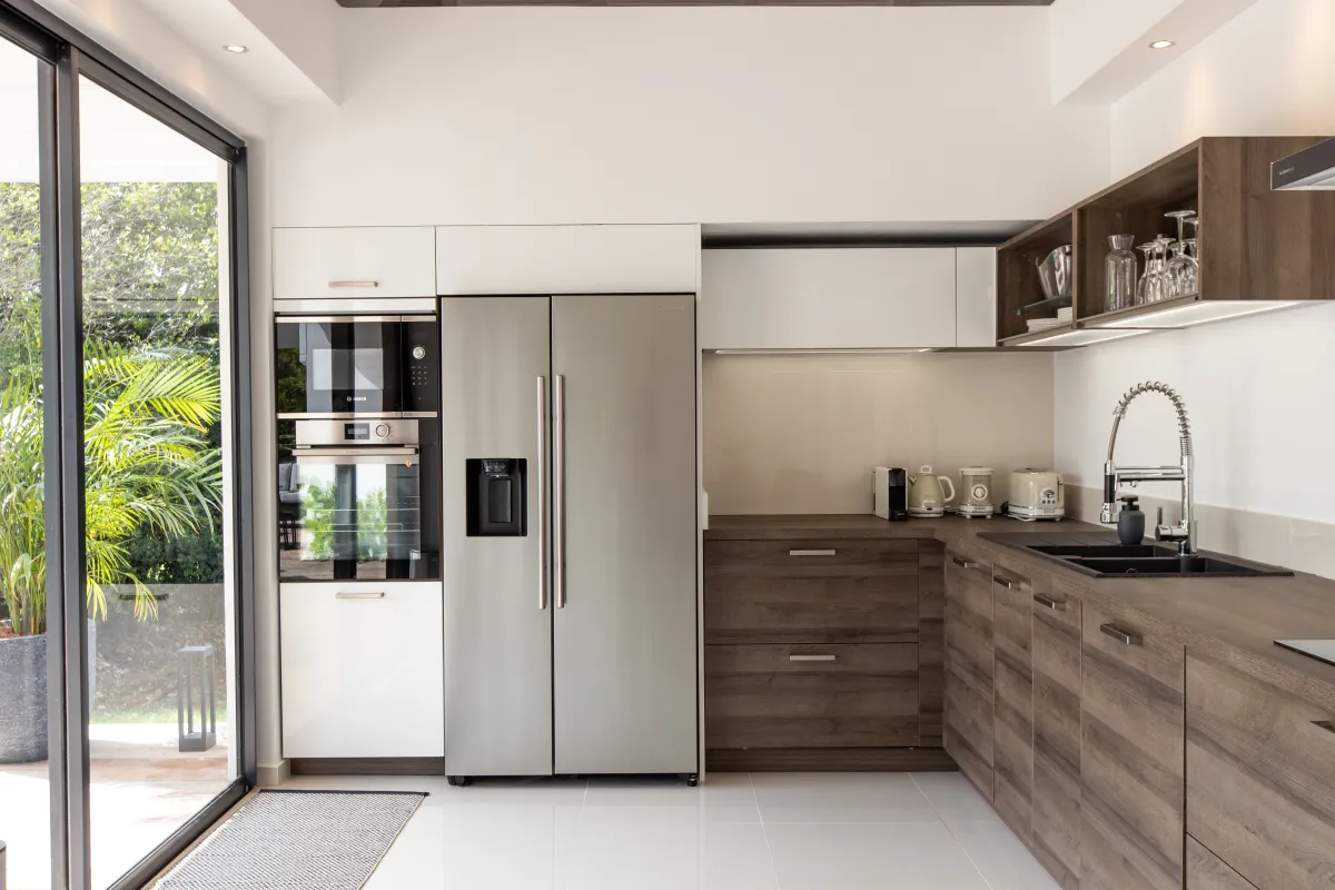Villa Nuit D'Etoiles: Modern kitchen with wood-grain cabinets stainless steel refrigerator and built-in ovens
