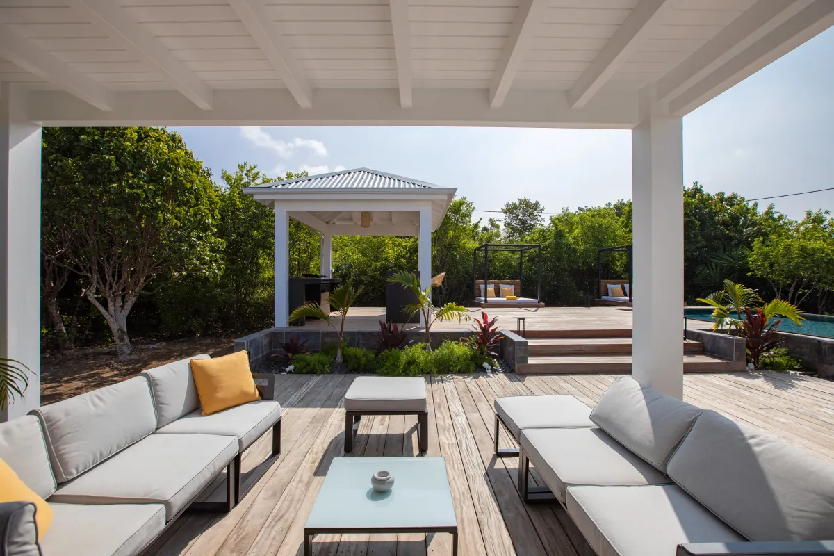 Villa Nuit D'Etoiles: Covered wooden terrace with outdoor lounge seating facing a gazebo and garden
