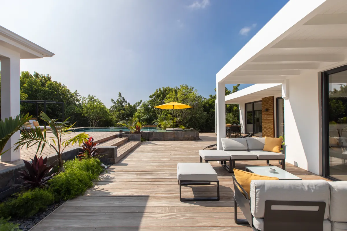 Villa Nuit D'Etoiles: Spacious wooden deck terrace with contemporary lounge seating overlooking a swimming pool and tropical garden