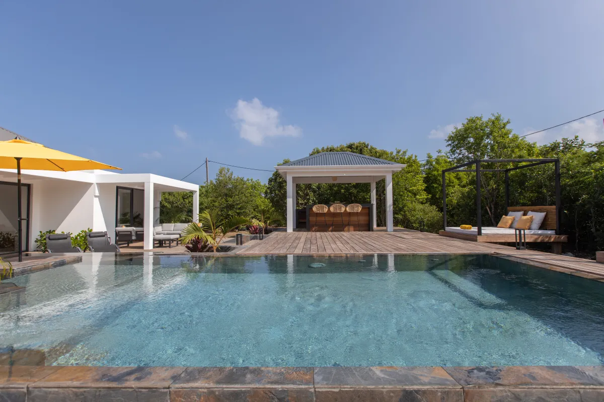 Villa Nuit D'Etoiles: Swimming pool with wooden sun deck, outdoor bar pavilion, and daybed under clear skies