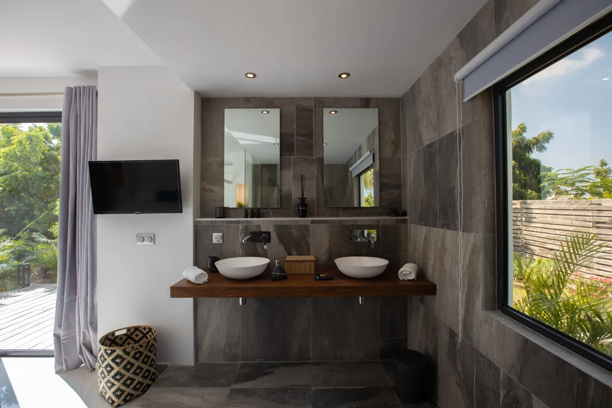 Villa Nuit D'Etoiles: Double vessel sinks on a wooden floating vanity with dark tiled walls and mirrors