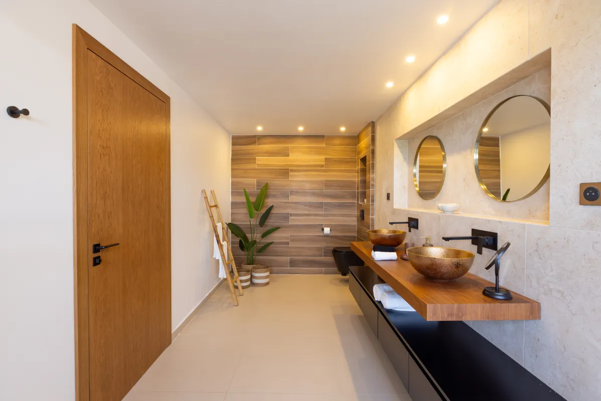 Villa Nuit Jade: Modern bathroom with double vessel sinks, round mirrors, and wood tile accent wall
