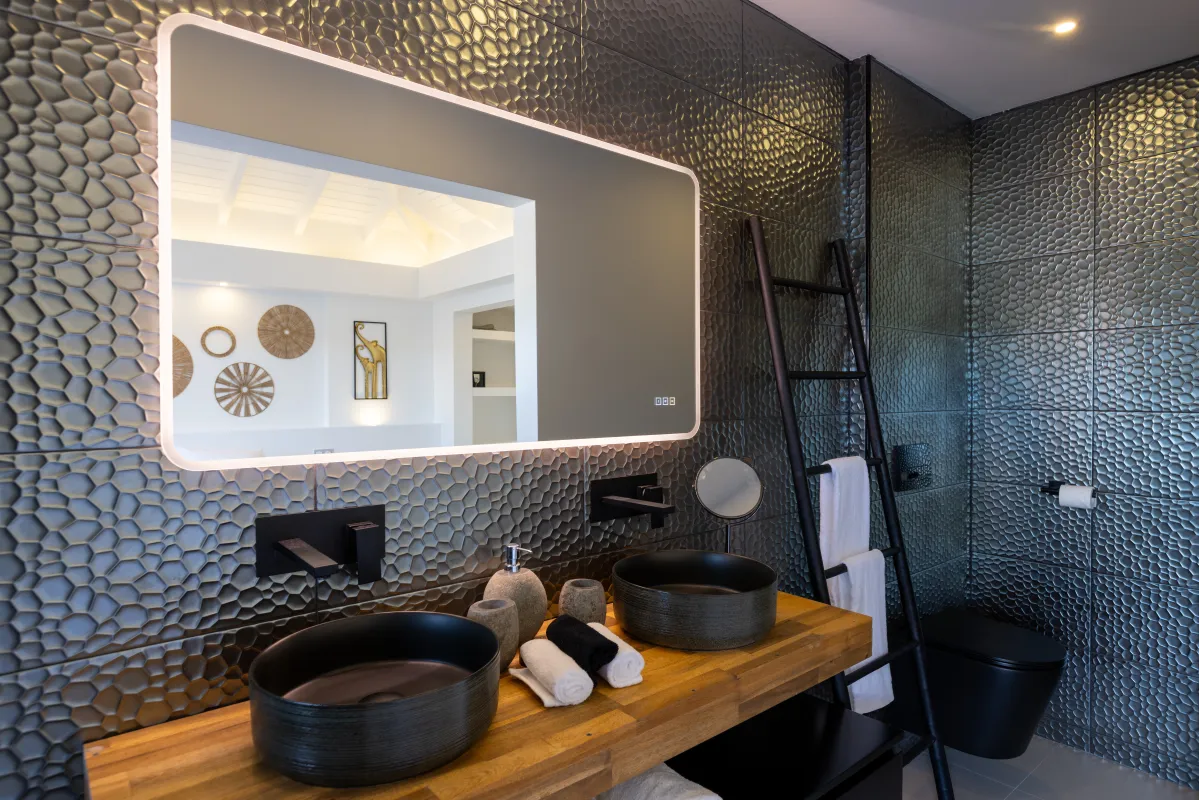 Villa Nuit Jade: Modern bathroom with double vessel sinks, wood vanity, backlit mirror, and textured wall tiles