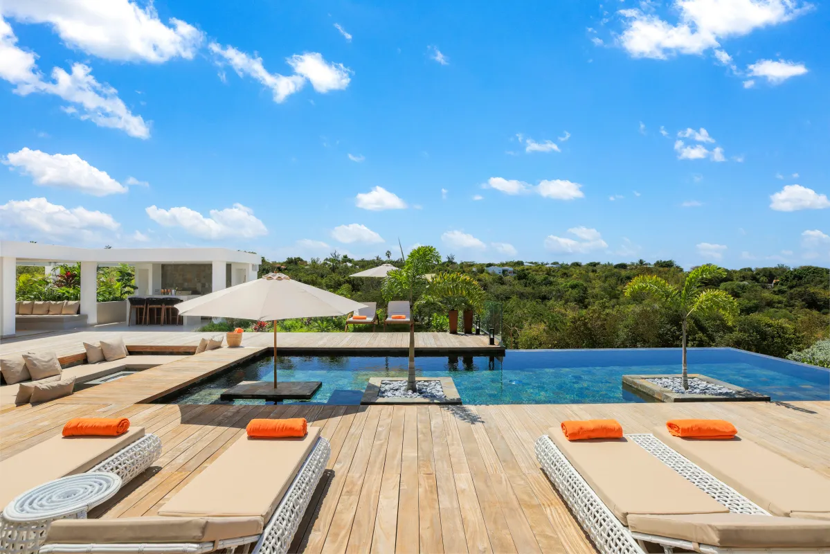 Villa Nuit Jade: Sun loungers on a wooden deck beside an infinity pool overlooking lush tropical hills