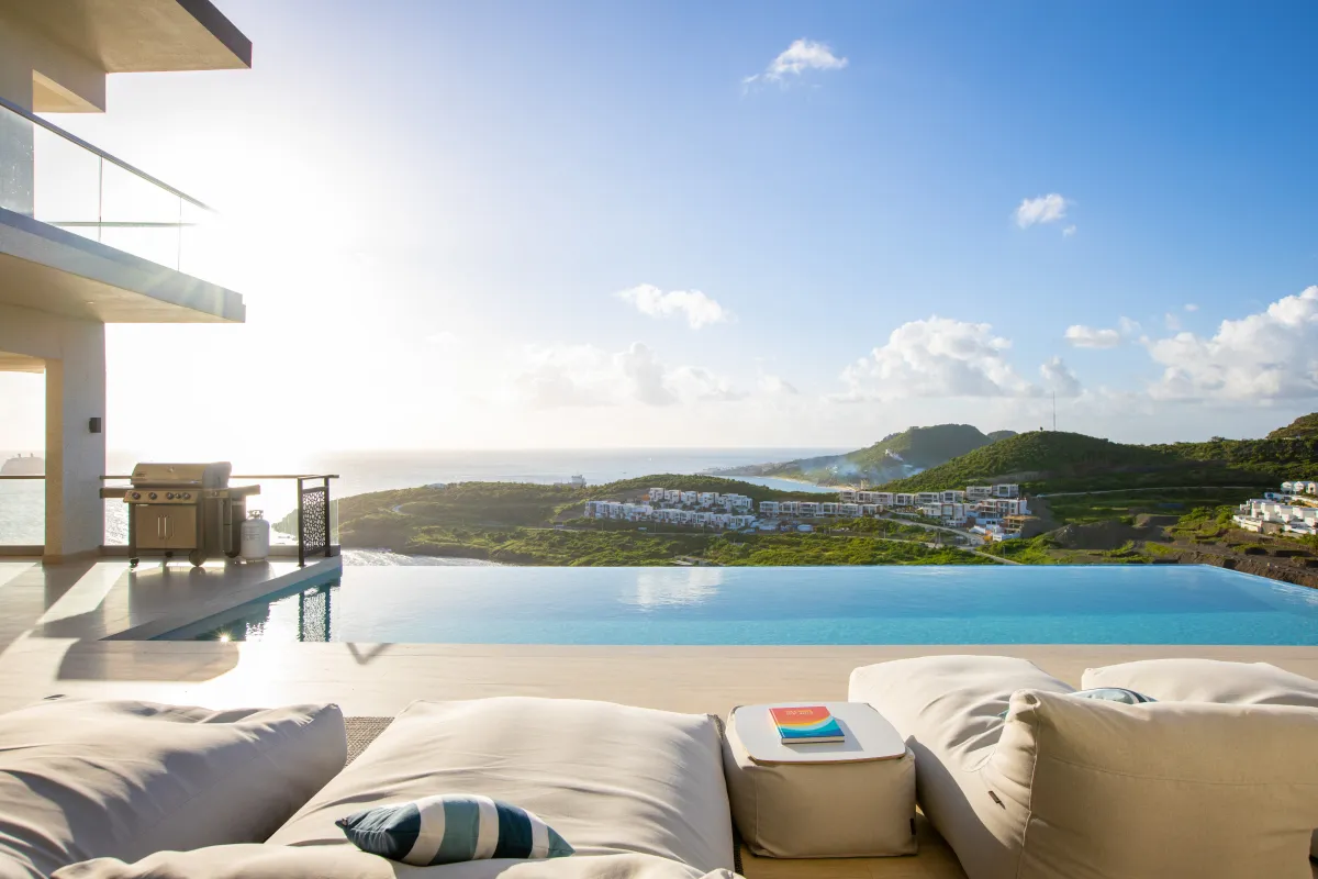 Villa Numa: Infinity pool and outdoor lounge cushions overlooking coastal hills and the ocean