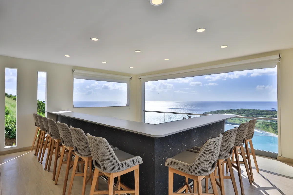 Villa Numa: Bar counter lined with high stools facing panoramic windows and an ocean view