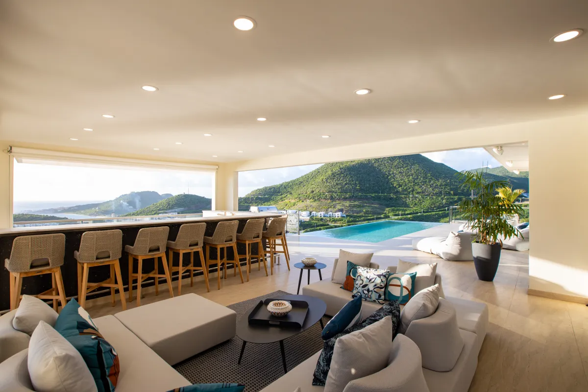 Villa Numa: Open-concept living room and bar seating overlooking an infinity pool and green hills