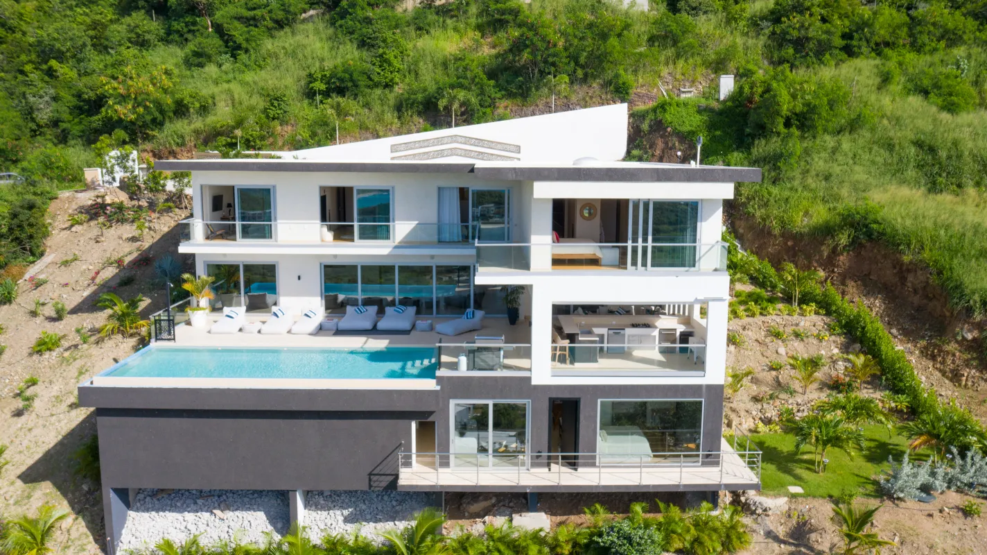 Villa Numa: Aerial view of a modern multi-level hillside villa with an infinity pool and sun loungers