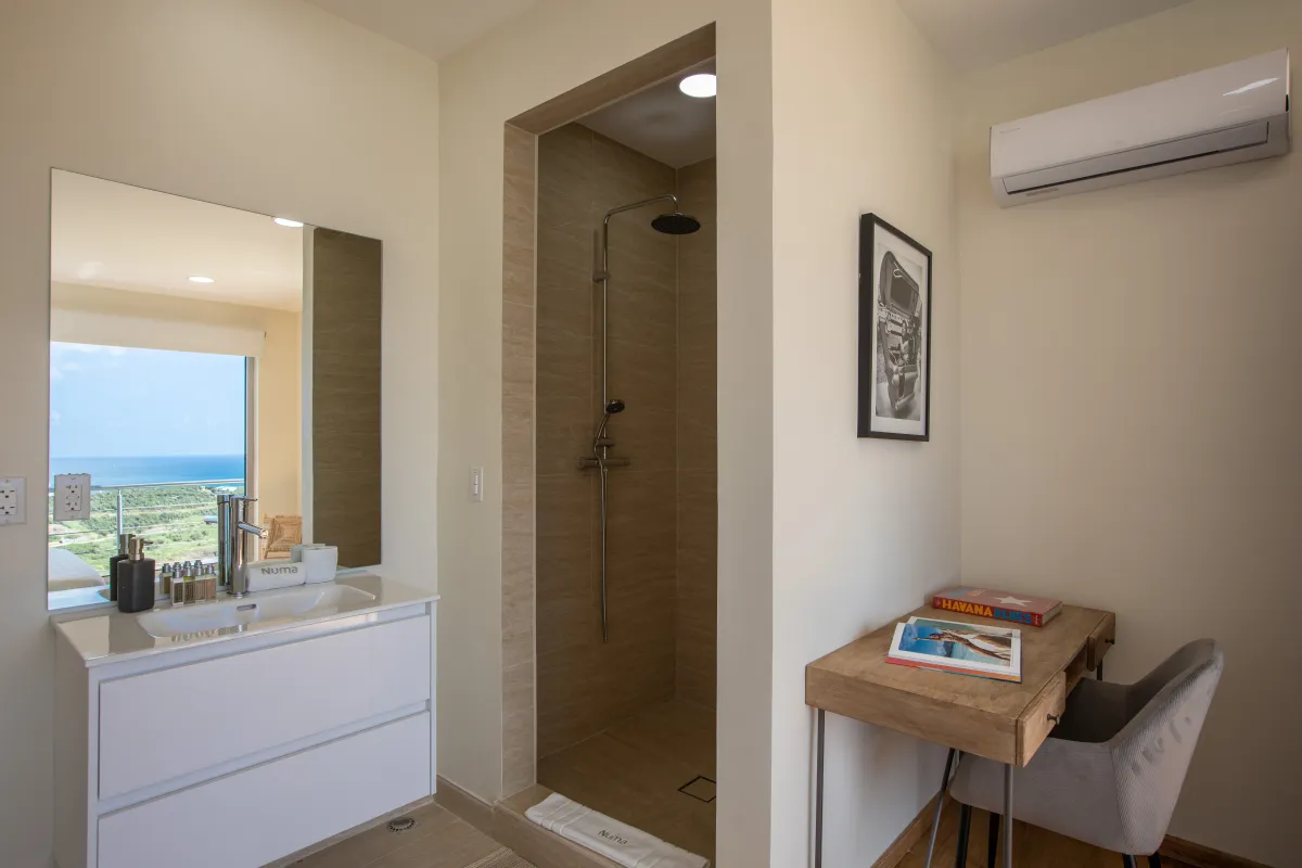 Villa Numa: Modern bathroom vanity and walk-in shower alongside a wooden study desk and chair