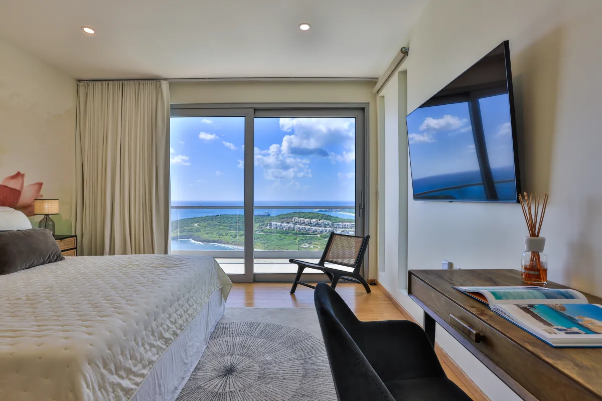 Villa Numa: Bedroom with bed, wall-mounted television, and sliding glass doors overlooking the ocean
