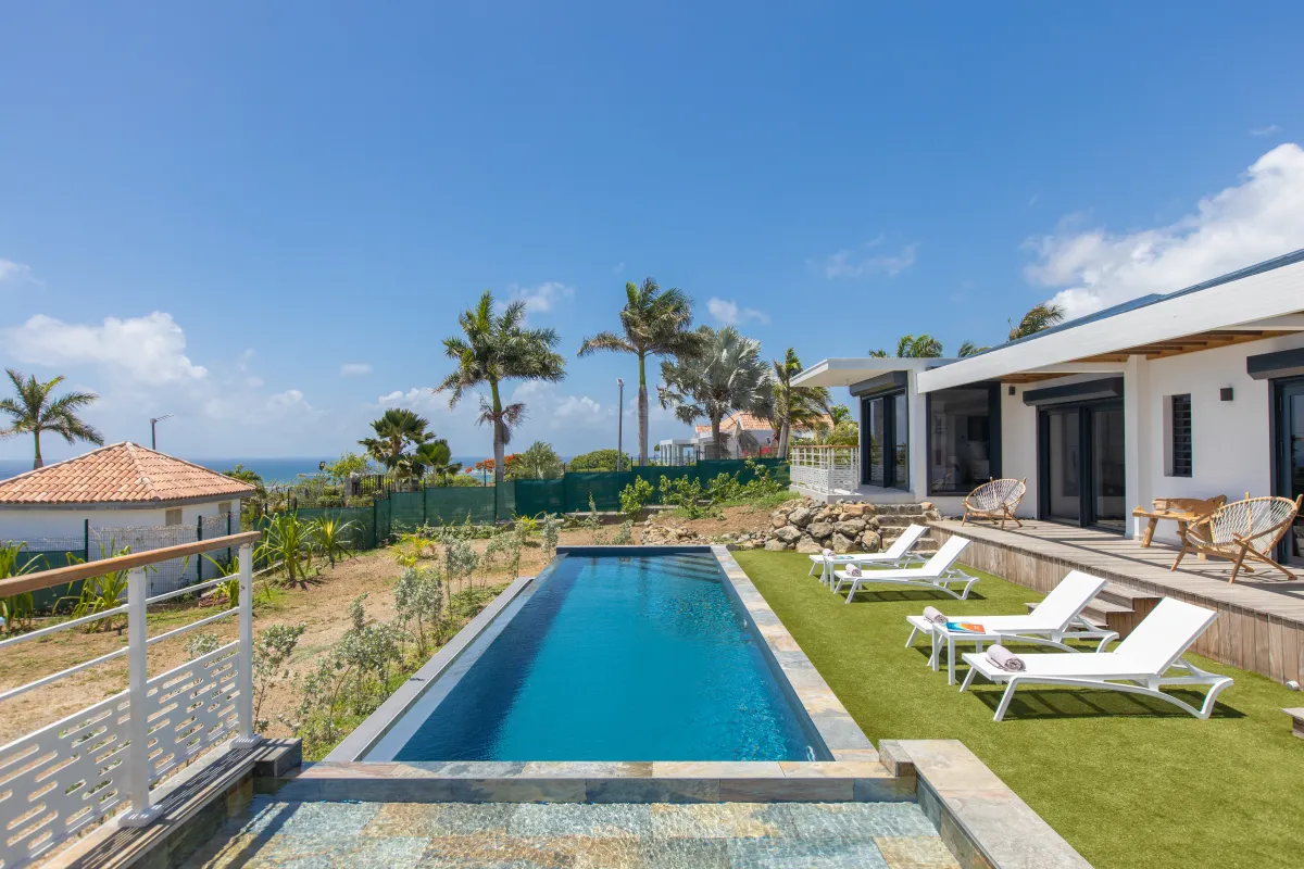 Villa Ocean's One: Rectangular swimming pool and white lounge chairs beside a villa overlooking the sea