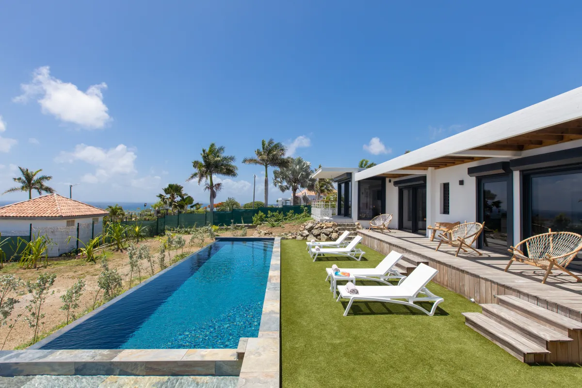 Villa Ocean's One: Long lap swimming pool and sun loungers on a lawn beside a modern villa