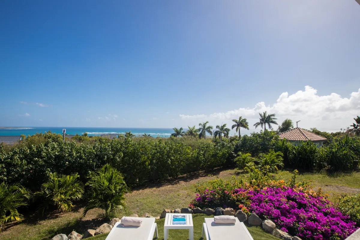Villa Ocean's One: Sun loungers overlooking tropical gardens and the ocean under a clear blue sky