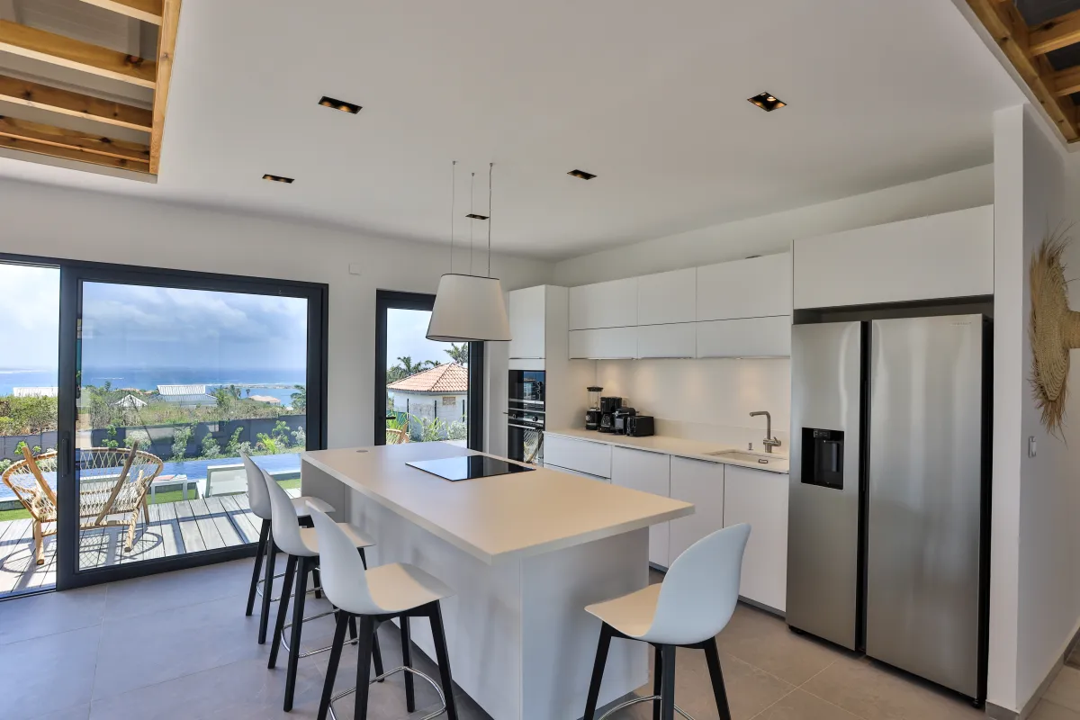 Villa Ocean's One: Modern white kitchen with a center island and views of the sea through glass doors