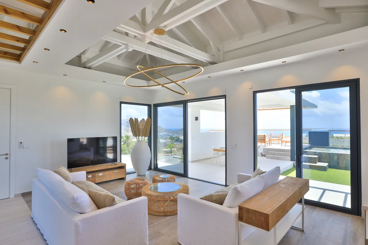Villa Ocean's One: Living room with white sofas, high vaulted ceiling, and sliding glass doors to the terrace