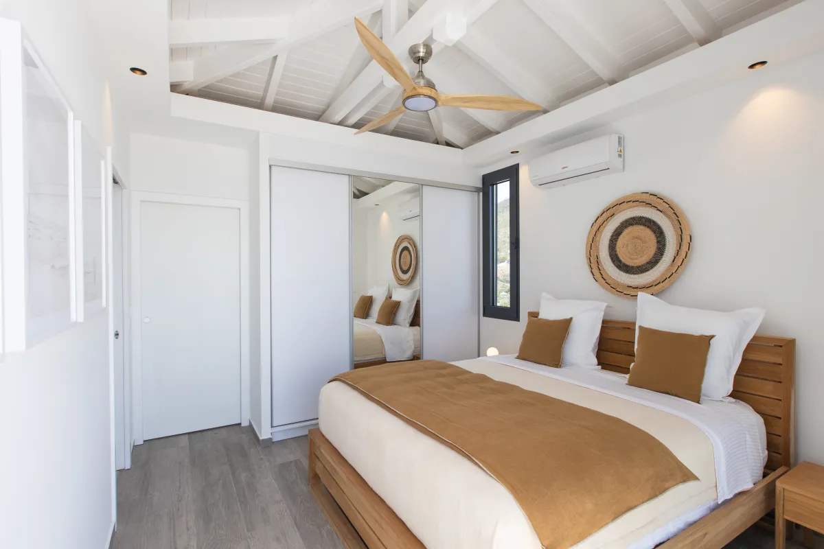 Villa Ocean's One: Modern bedroom with wooden bed frame, ceiling fan, and sliding mirrored closet doors