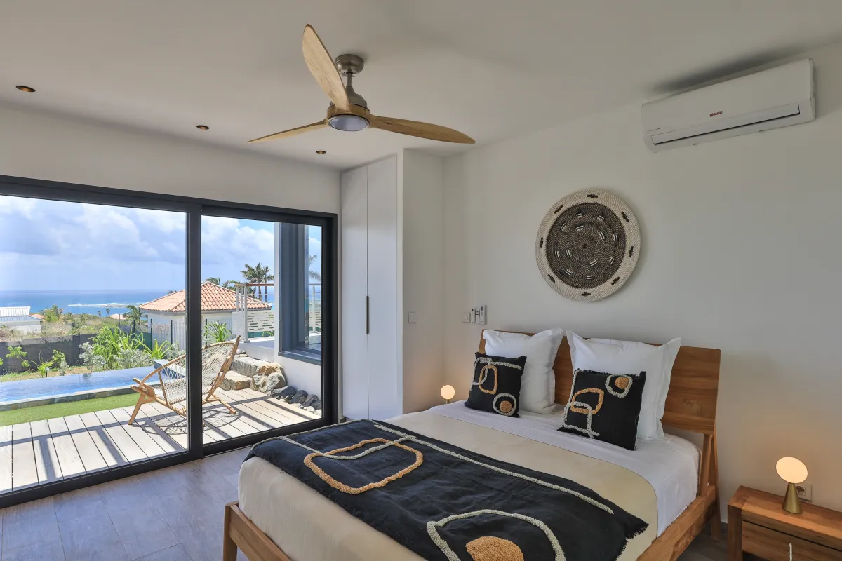 Villa Ocean's One: Bedroom with wooden bed frame and sliding glass doors opening to a pool deck