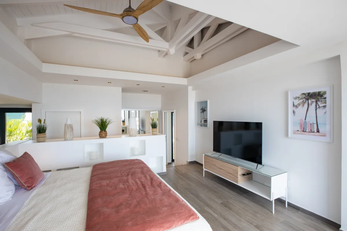 Villa Ocean's One: Bedroom with high exposed beam ceiling, large bed, and television on a white stand