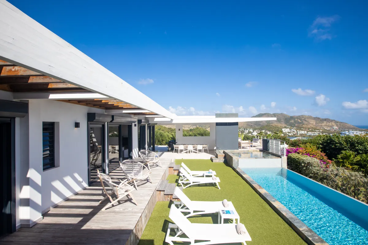 Villa Ocean's One: Sun deck with lounge chairs next to a lap pool overlooking hills and ocean