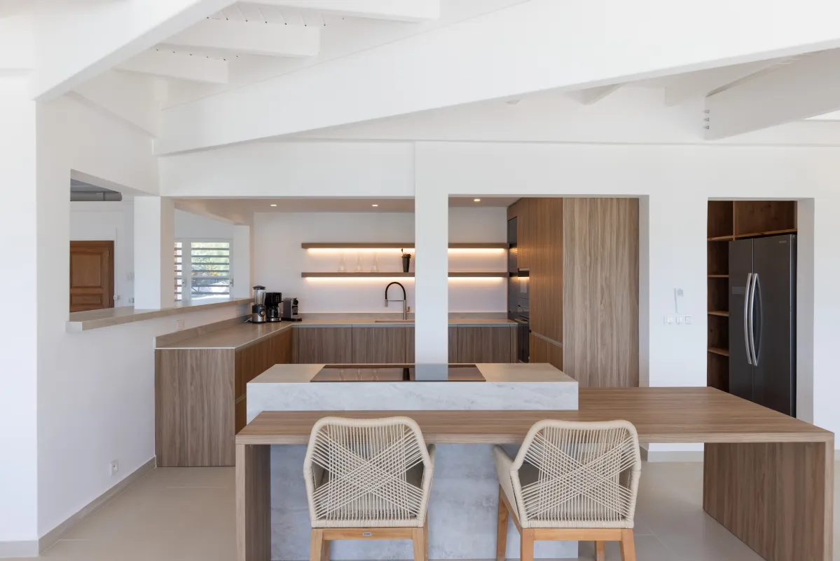 Villa Osun: Modern open-plan kitchen with wooden cabinetry, island counter, and breakfast bar seating